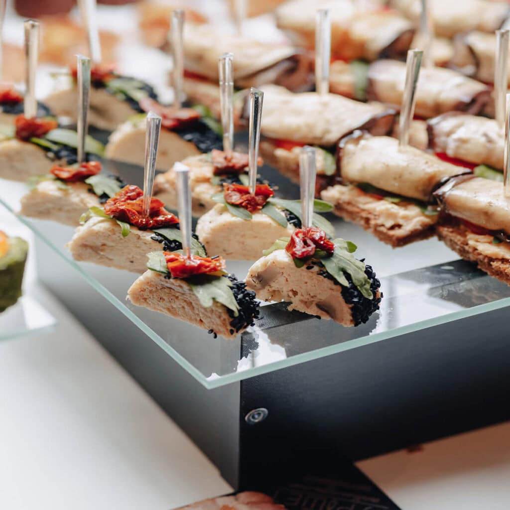Delikatne przekąski na eleganckim talerzu z warstwami mięsa, warzyw i sosem, idealne na imprezy i spotkania towarzyskie.