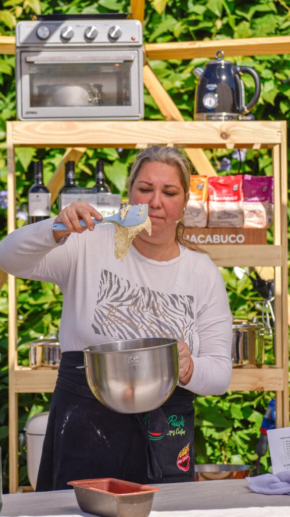 Szczęśliwa kobieta gotuje w kuchni plenerowej podczas wydarzenia kulinarnego na świeżym powietrzu.