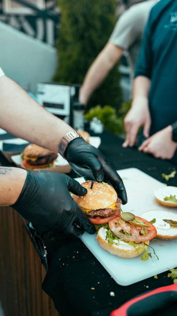 Smaczne burgery przygotowywane na zewnątrz z dbaniem o higienę. Uczta dla smakoszy podczas relaksu na świeżym powietrzu.