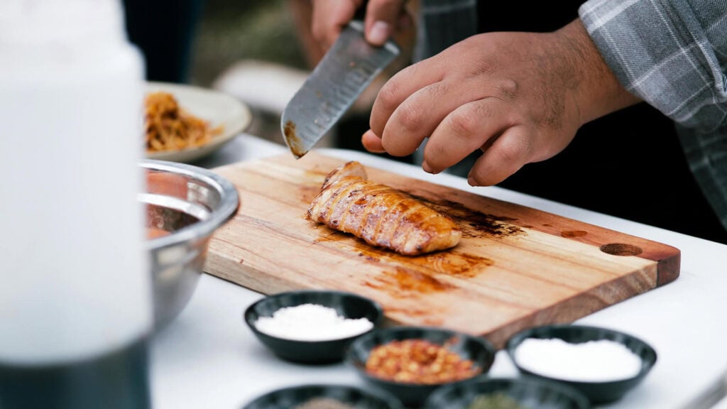 Delicious grilled fish being prepared on a wooden cutting board during outdoor cooking.