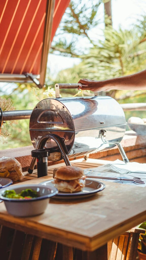 Piec do grillowania na świeżym powietrzu z mięsem i dodatkami na drewnianym stole.